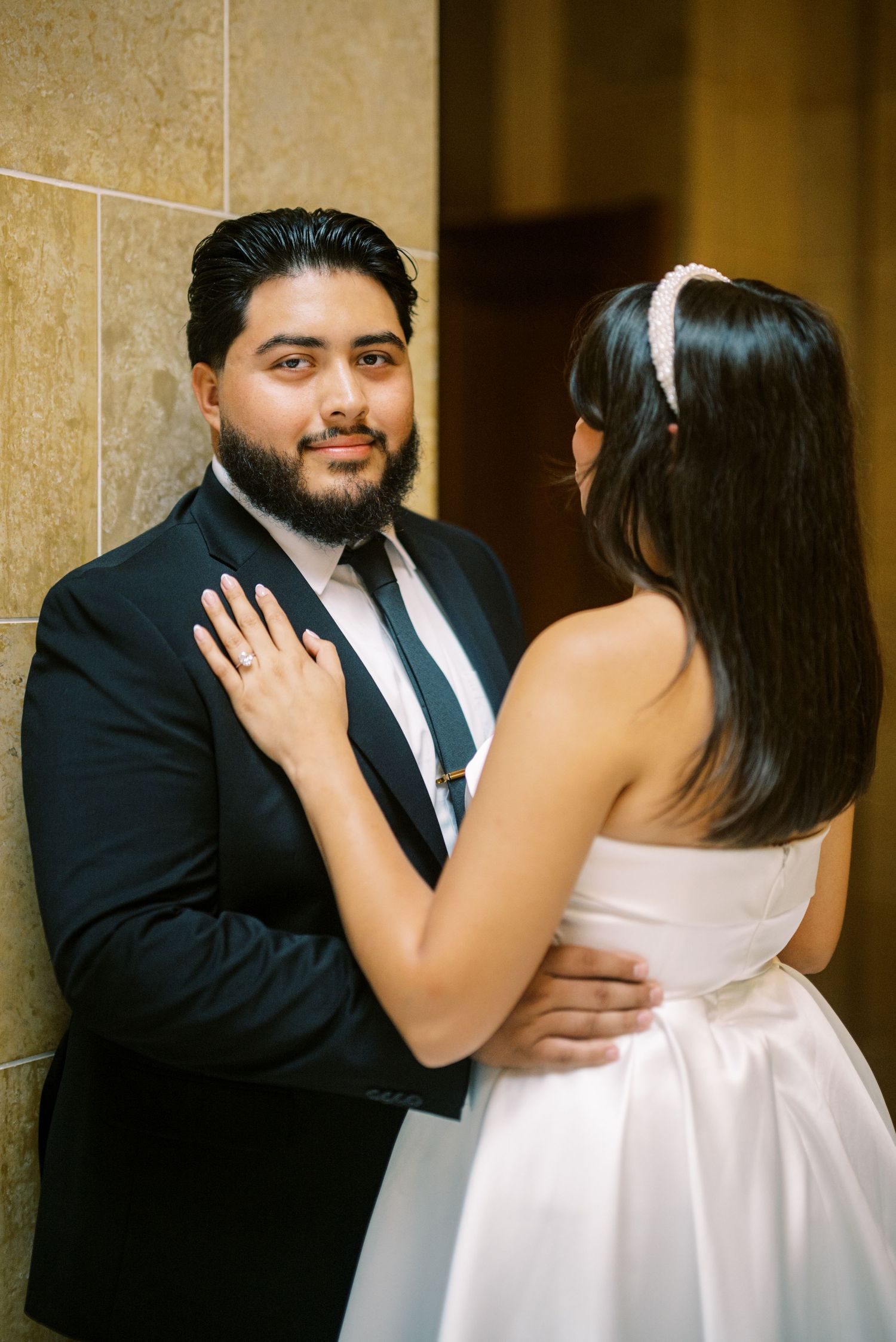 A couple in formal attire sharing an intimate moment in a marble hallway.