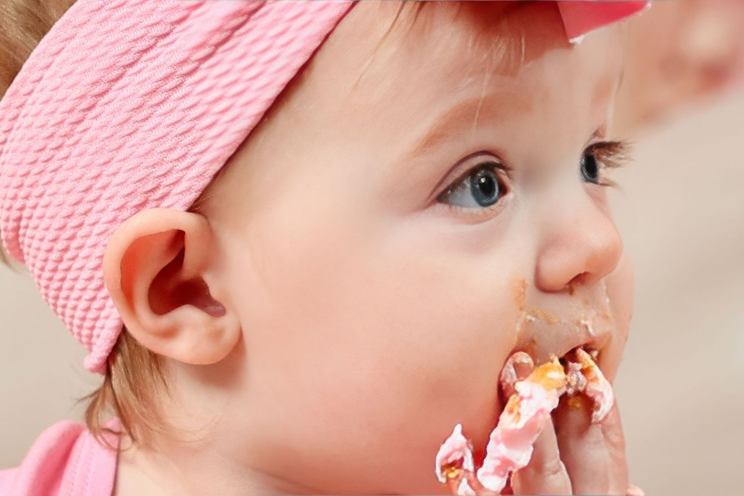 Small child in pink hat enjoys eating messy snack  Carlsbad Roswell Artesia Hobbs New Mexico NM cake smash bath first birthday picture