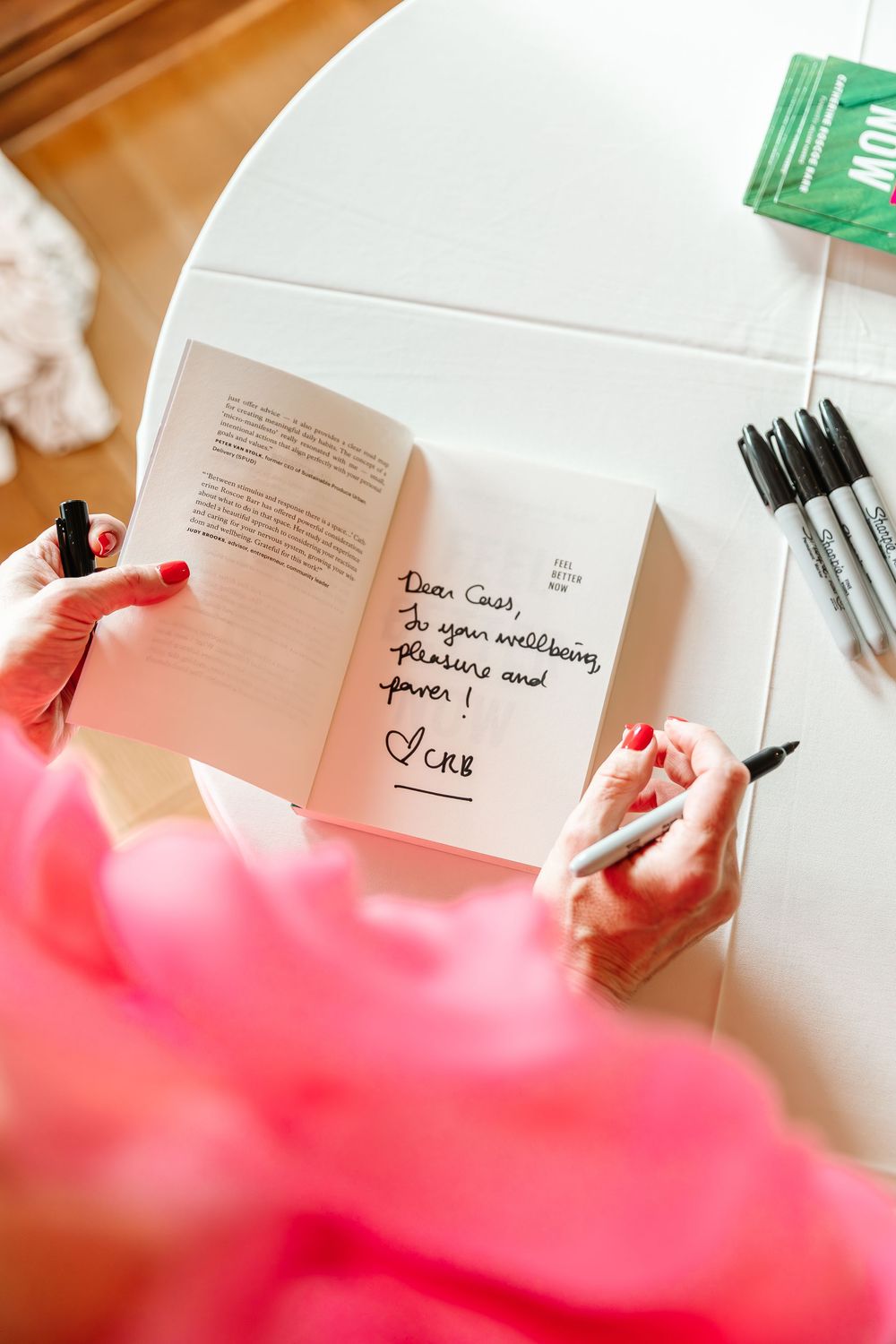 Close-up sequence of hands writing in an open book with a black pen against a pink-tinted background.