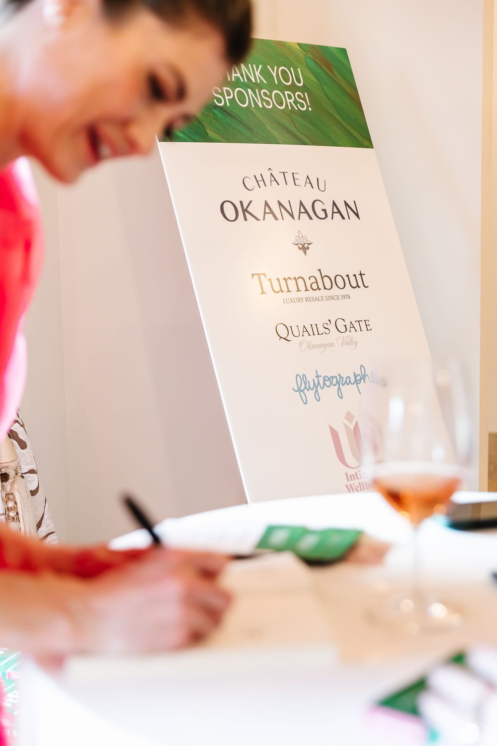 Event sponsor cards and signs displayed on a white surface including Quails Gate and Okanagan branding.