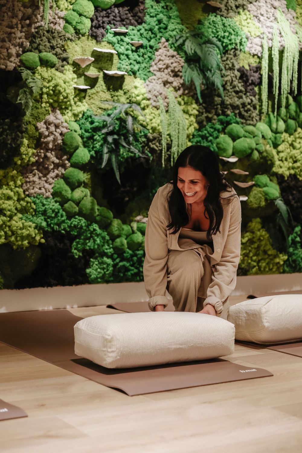 Someone arranges white cushions in a modern space with vertical garden walls.