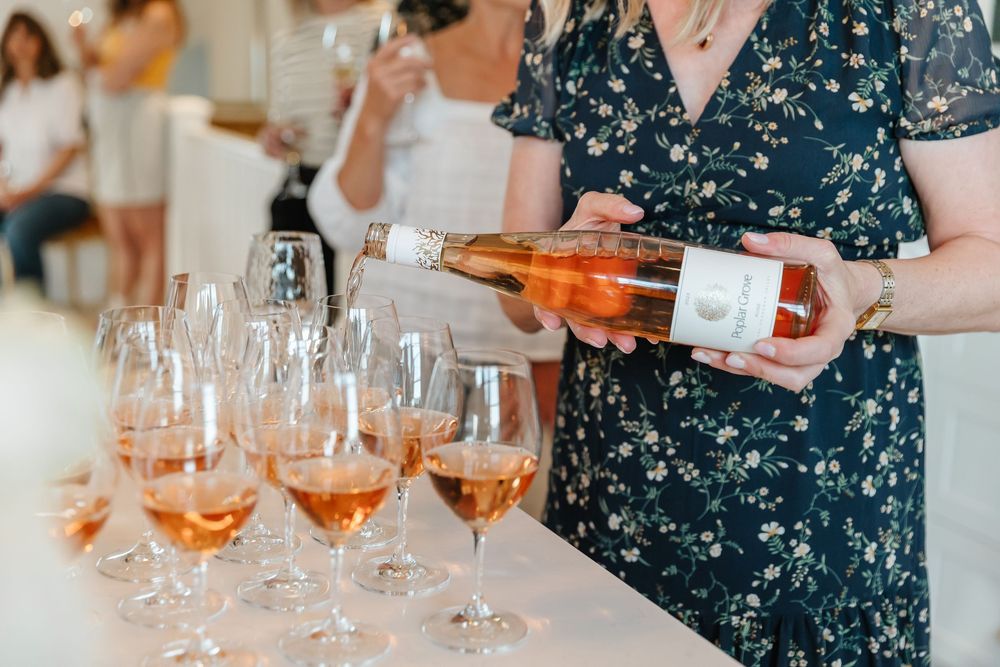 Wine glasses filled with rose being served on a table at an elegant event.