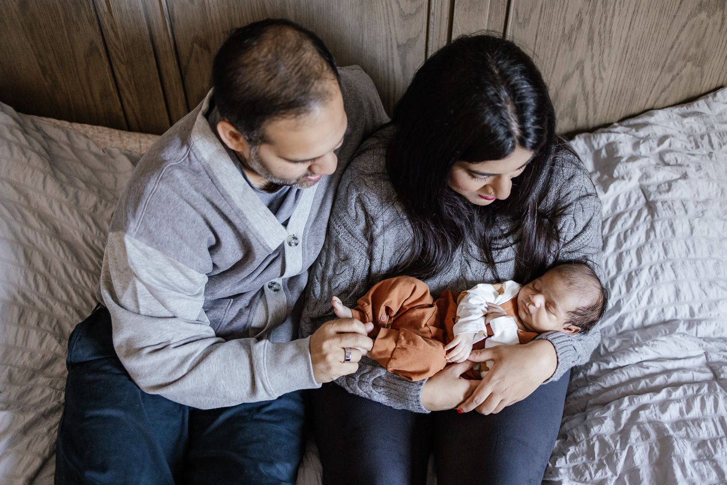 Family snuggles on their bed with their new baby at newborn photoshoot