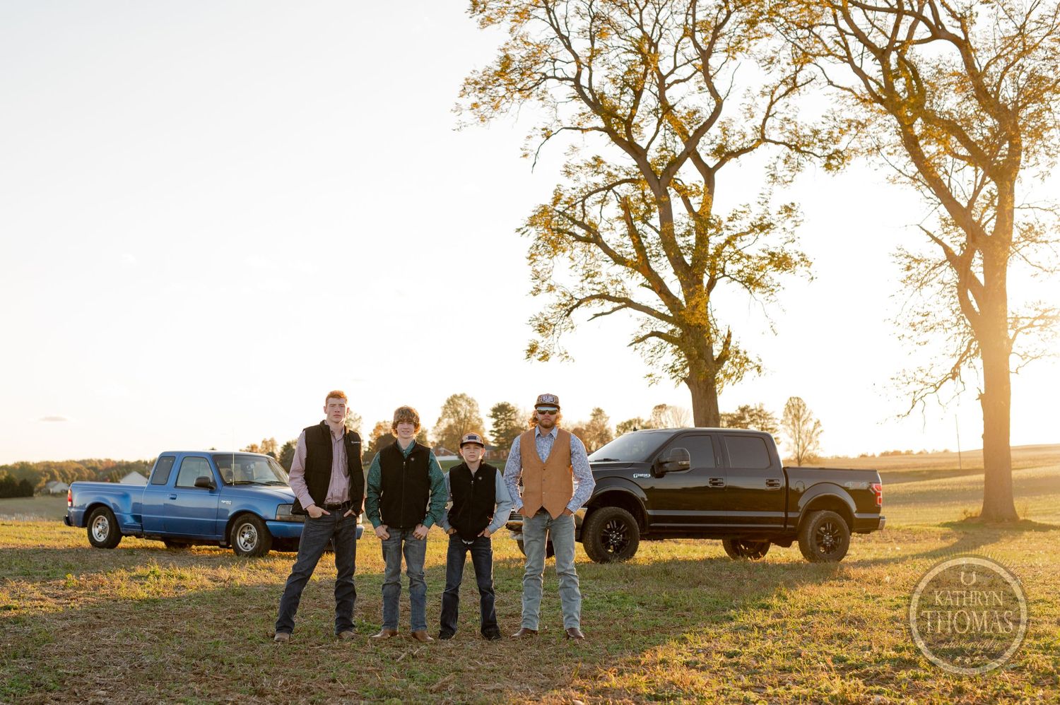 Group photo with family members standing together at sunset with trucks in background.