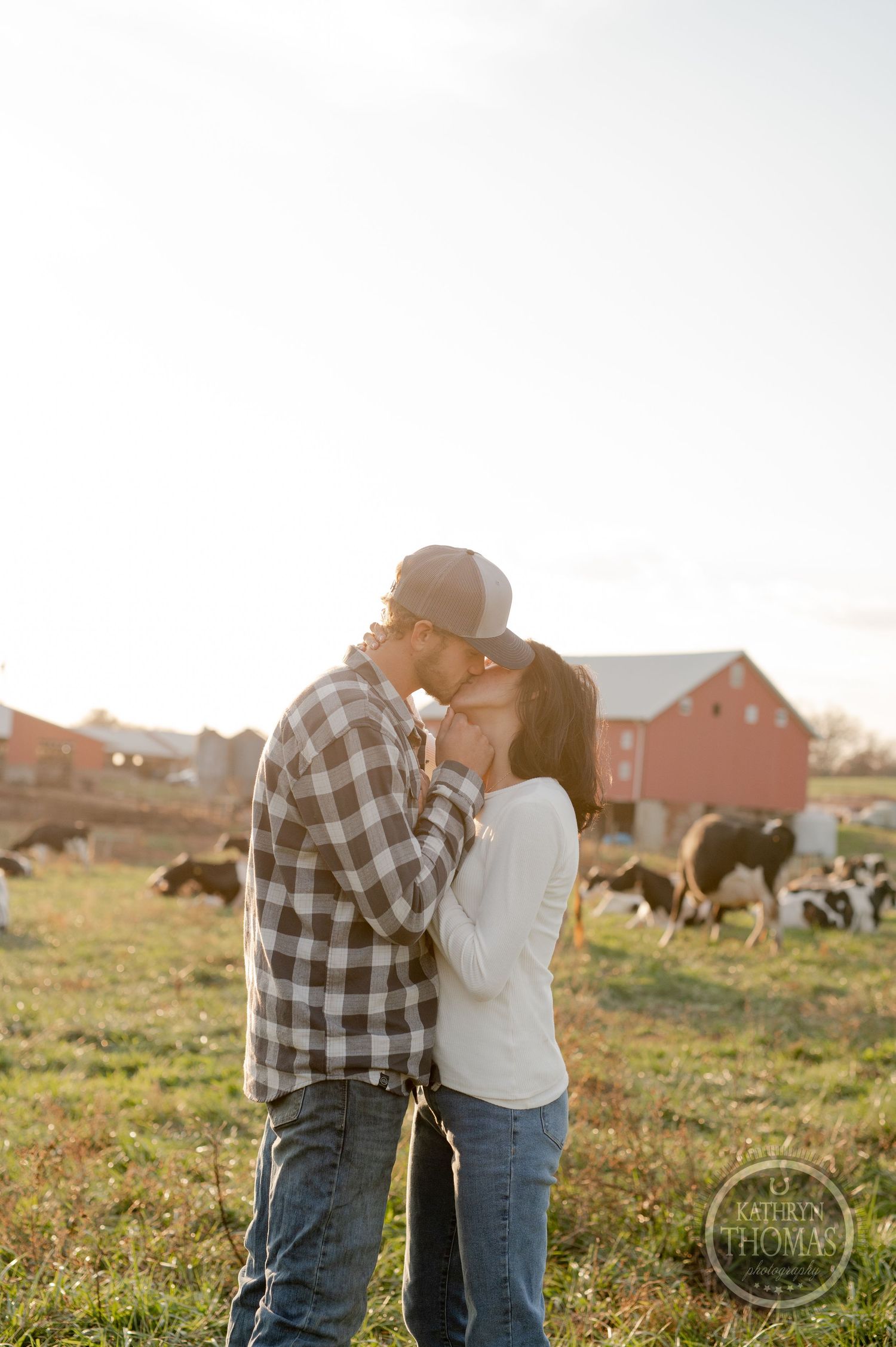A romantic moment shared between a couple on their farm during golden hour with cattle grazing nearby.