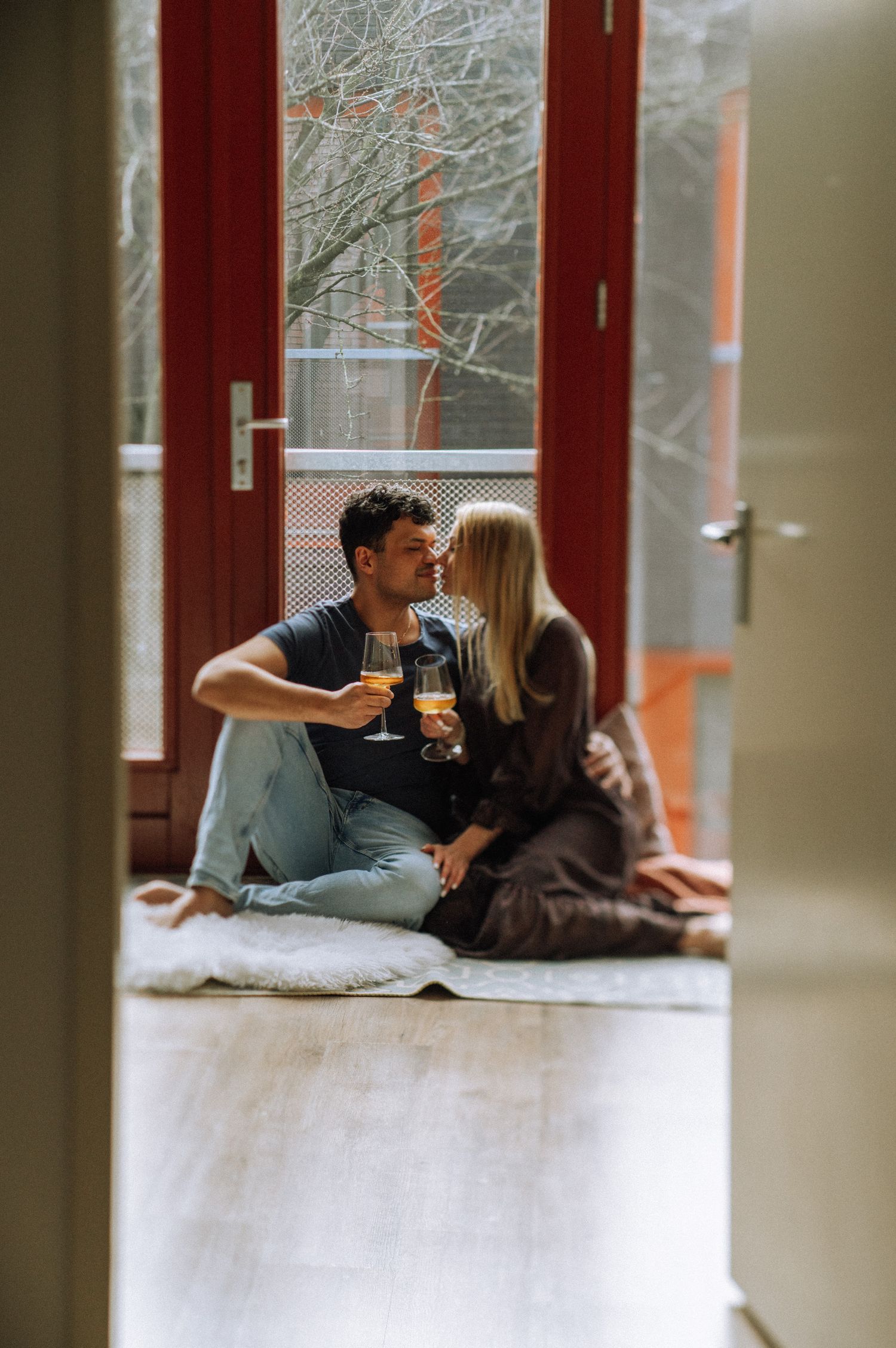 A couple relaxing together by large windows in a cozy indoor setting.