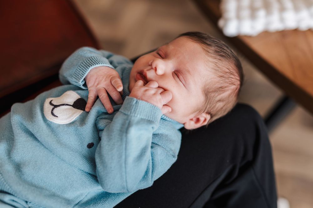 Peaceful newborn baby sleeping soundly while wearing soft blue sleepwear with teddy bear design.