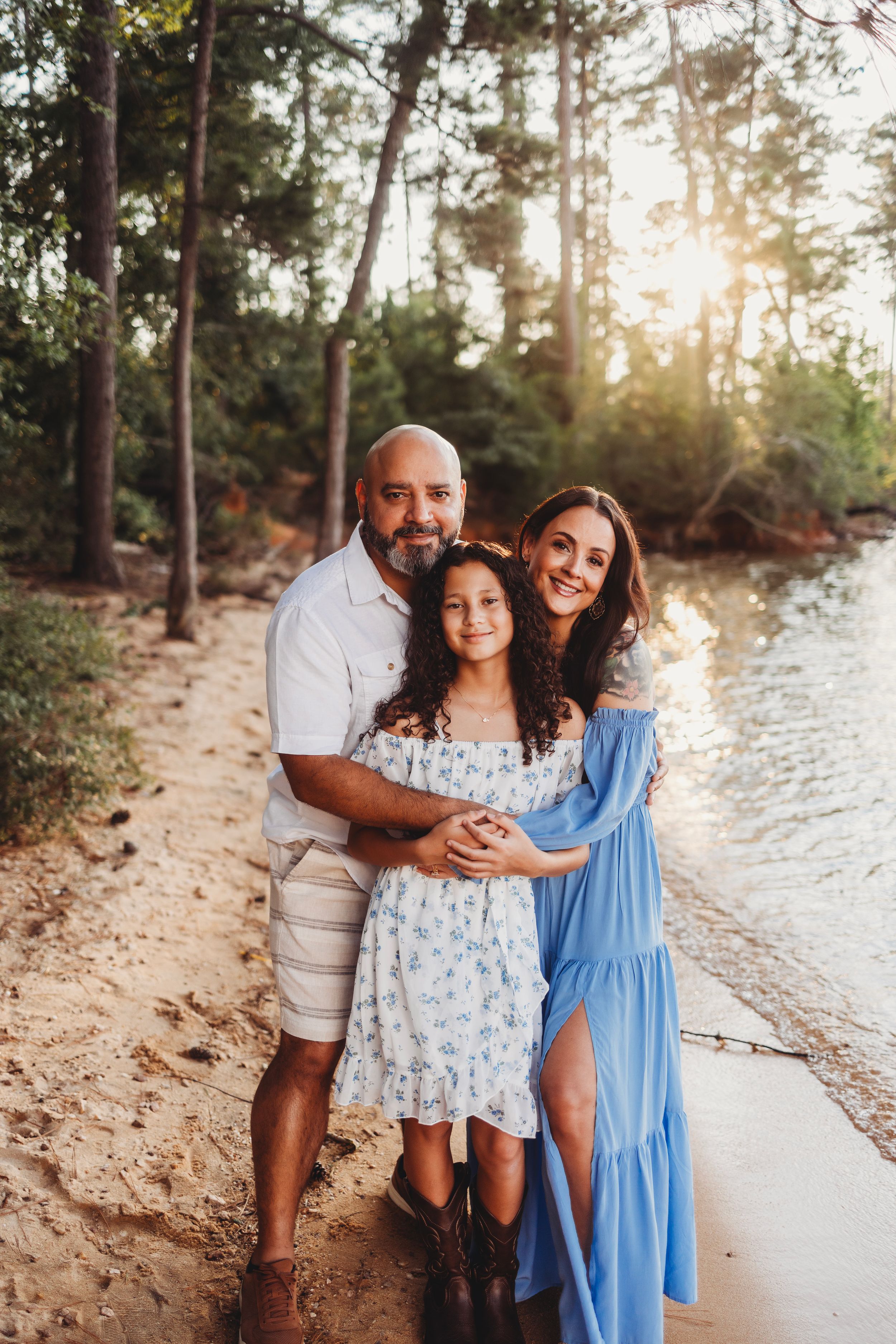 Family portrait on a beach path with pine trees and sunset lighting.