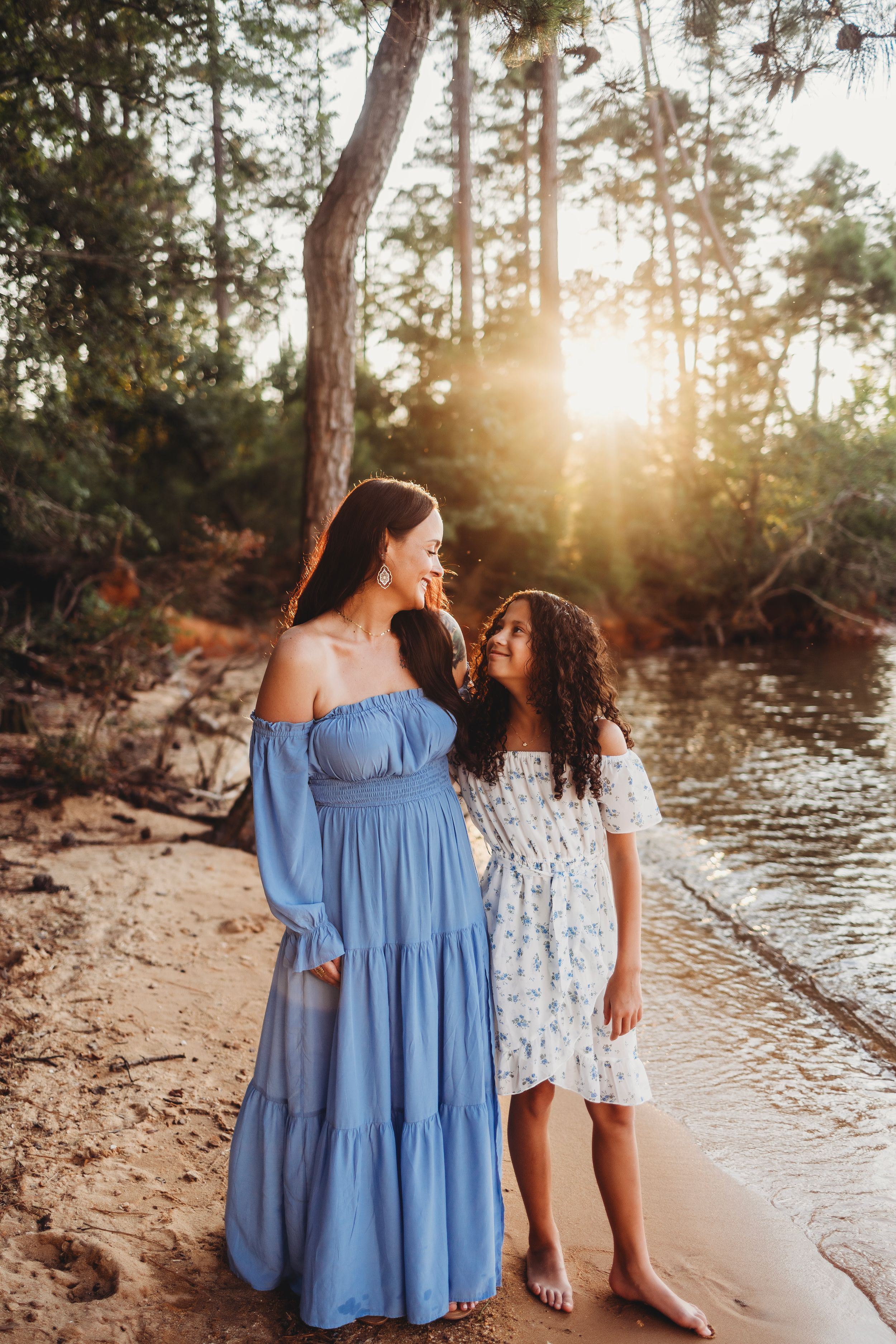 Mother and child in coordinating blue and white dresses by the water.
