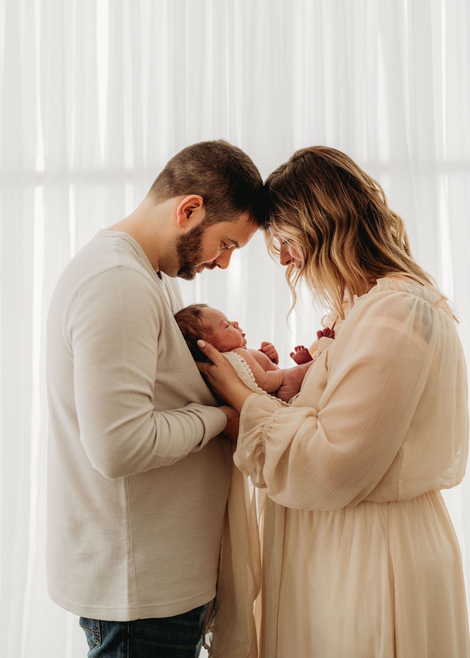 Intimate newborn photography session with soft window light and neutral tones.
