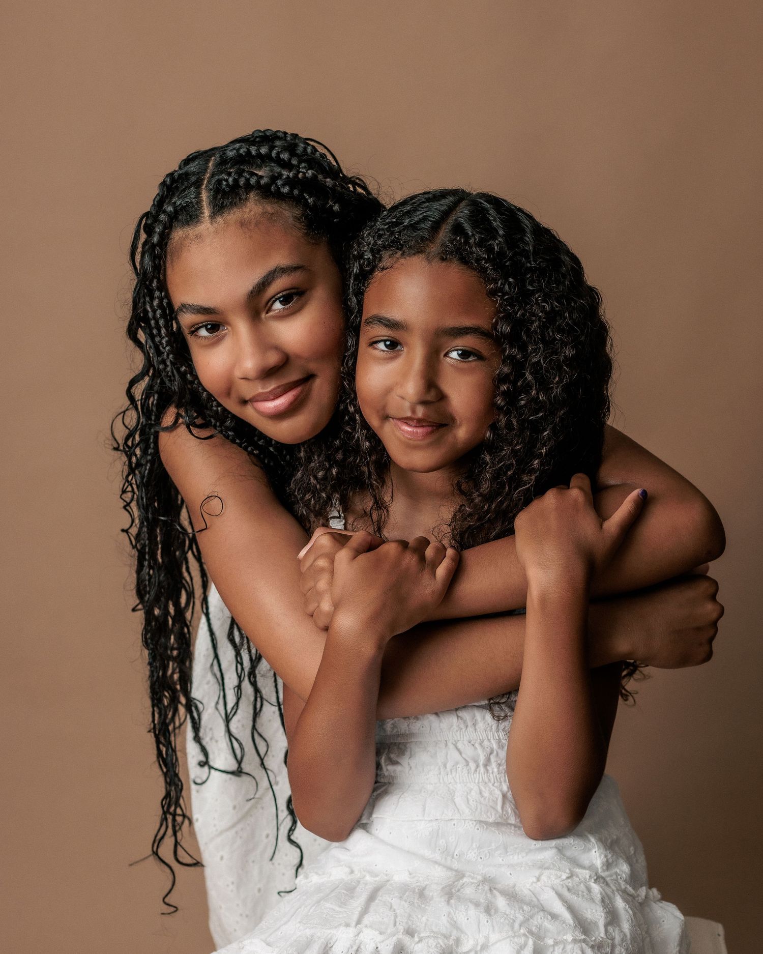 2 sisters embrace while posing for a family photography session in Cedar Park Texas. The session was done in Studio.