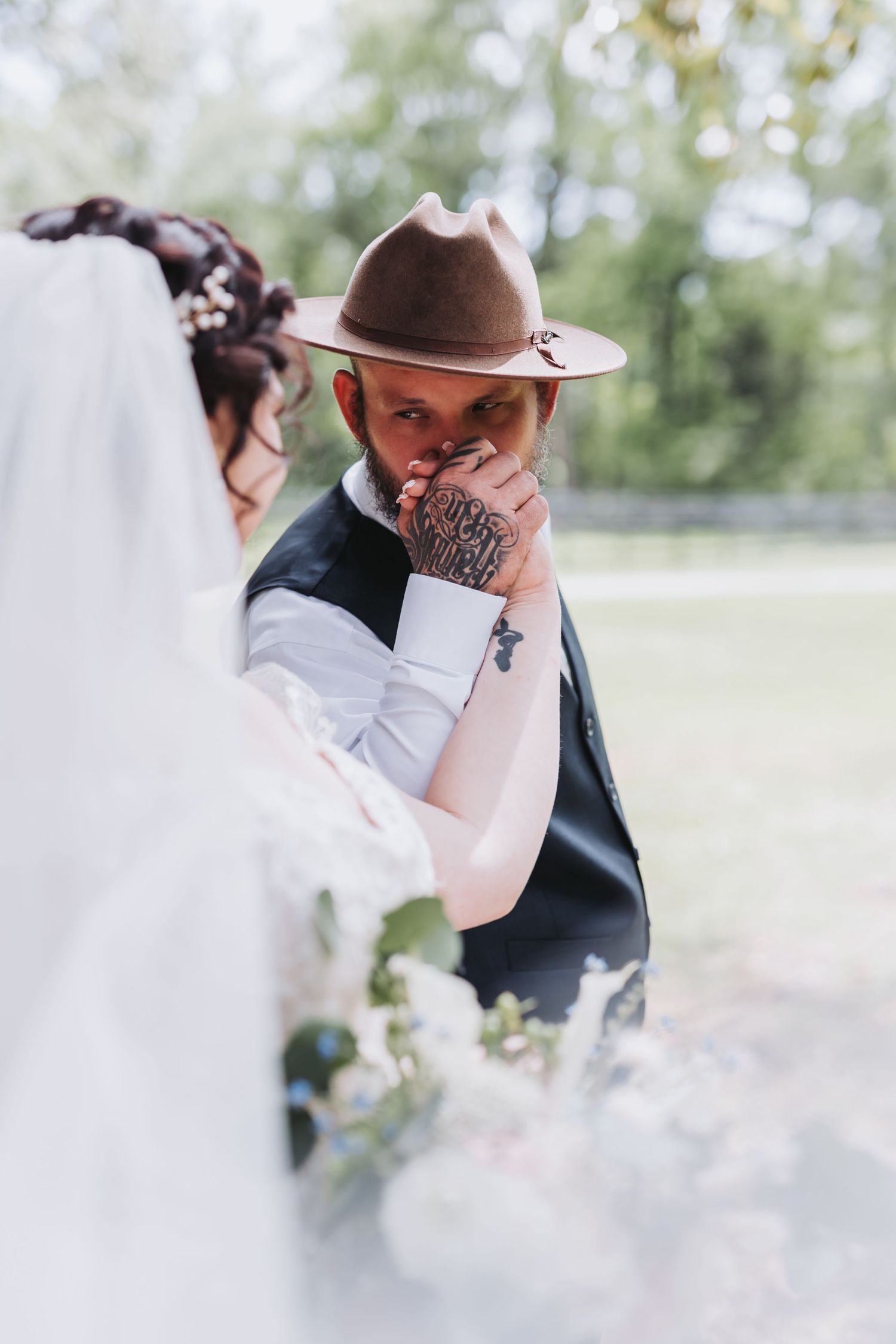 An emotional side profile of two people sharing a tender moment at an outdoor wedding ceremony.