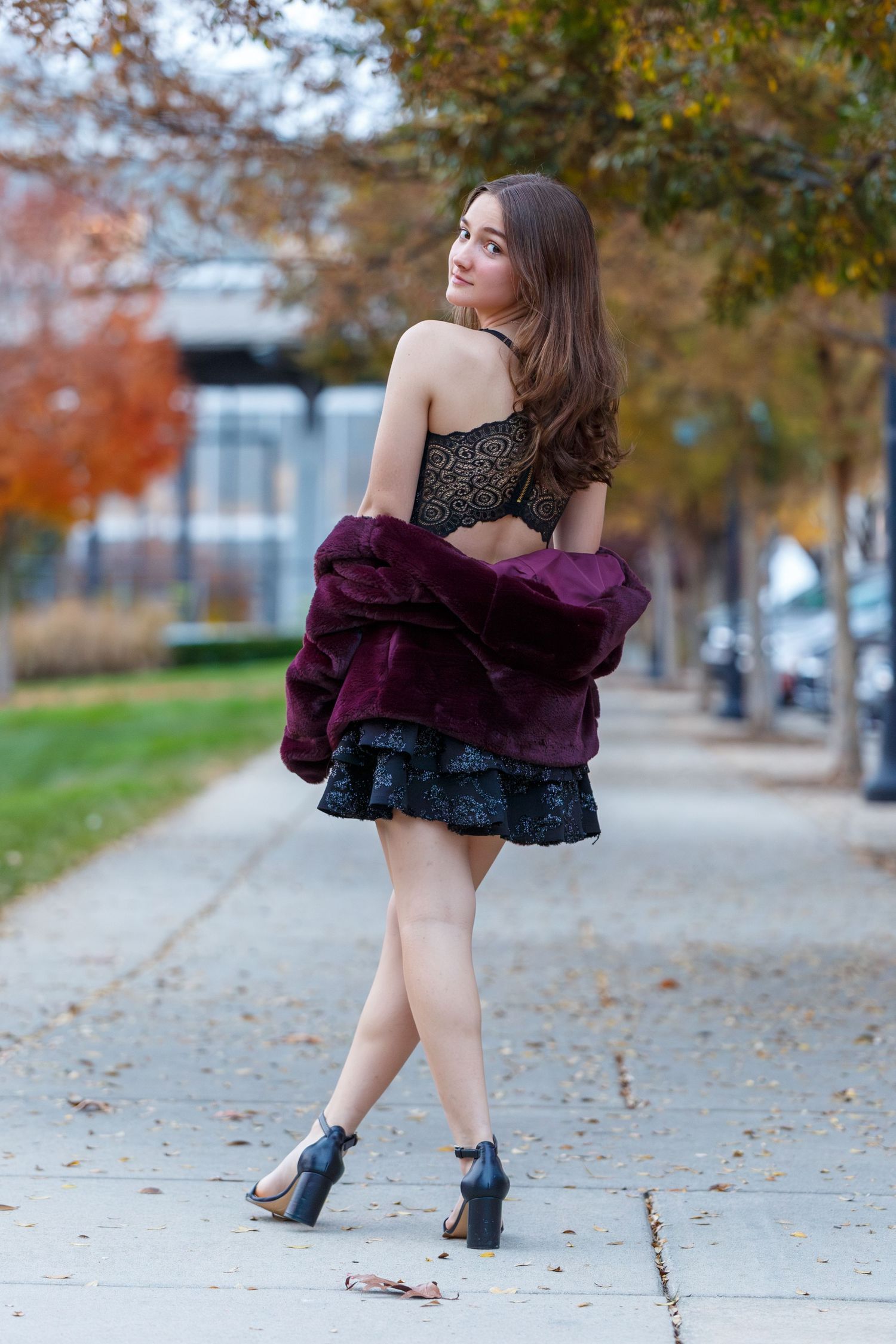 Stylish autumn fashion photo on tree-lined path with fall foliage.