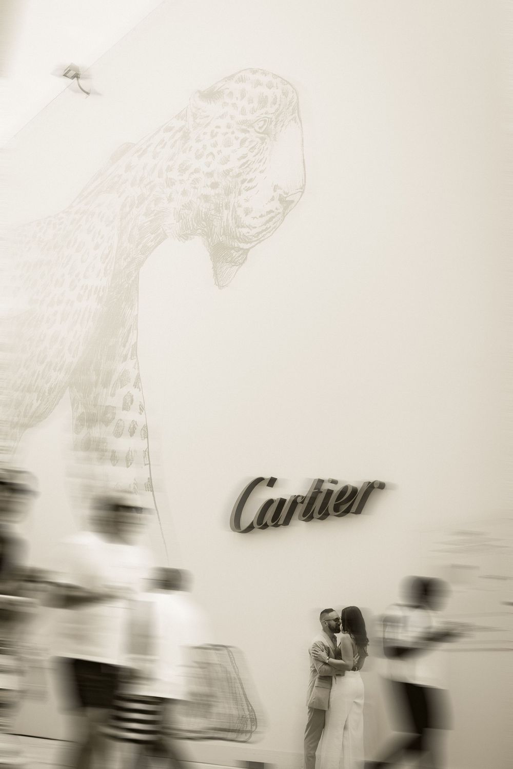 Blurred figures pass a Cartier store facade featuring an elegant leopard illustration in soft sepia tones.