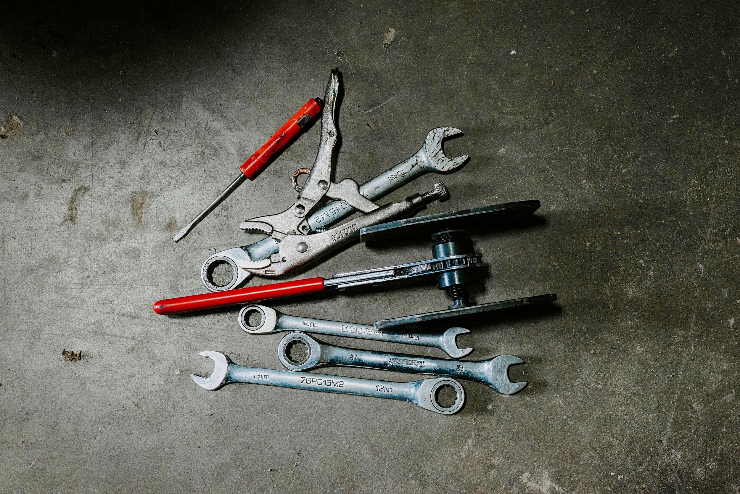 Sequence showing silver wrenches arranged from minimal to many tools lying on a dark textured surface.