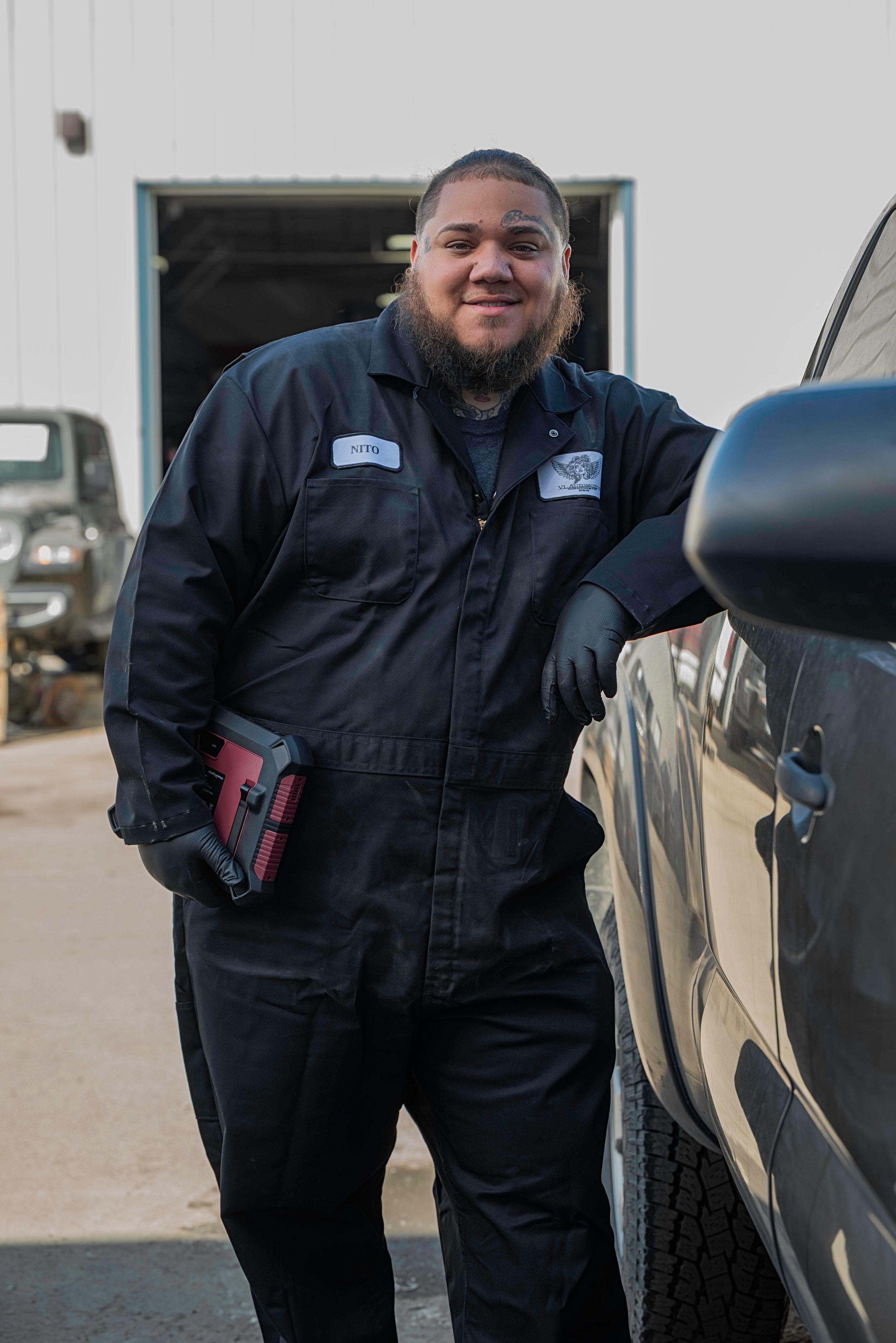 Security guard in a black vest uniform stands beside a parked vehicle in an outdoor setting.