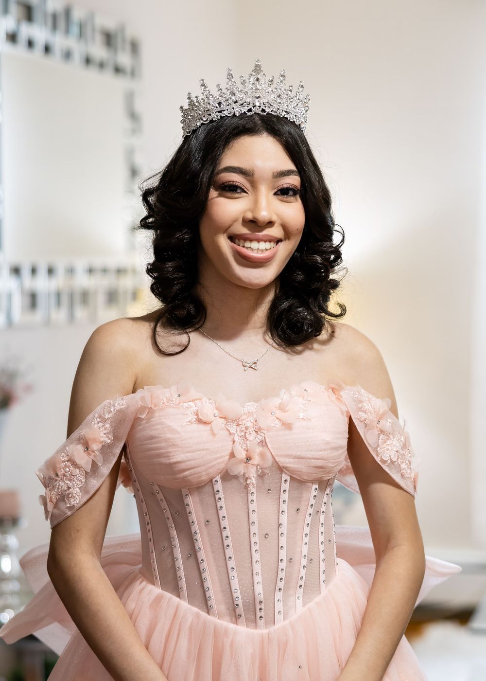 A glamorous pink ballgown with corset bodice and sparkly tiara crown in an indoor setting.