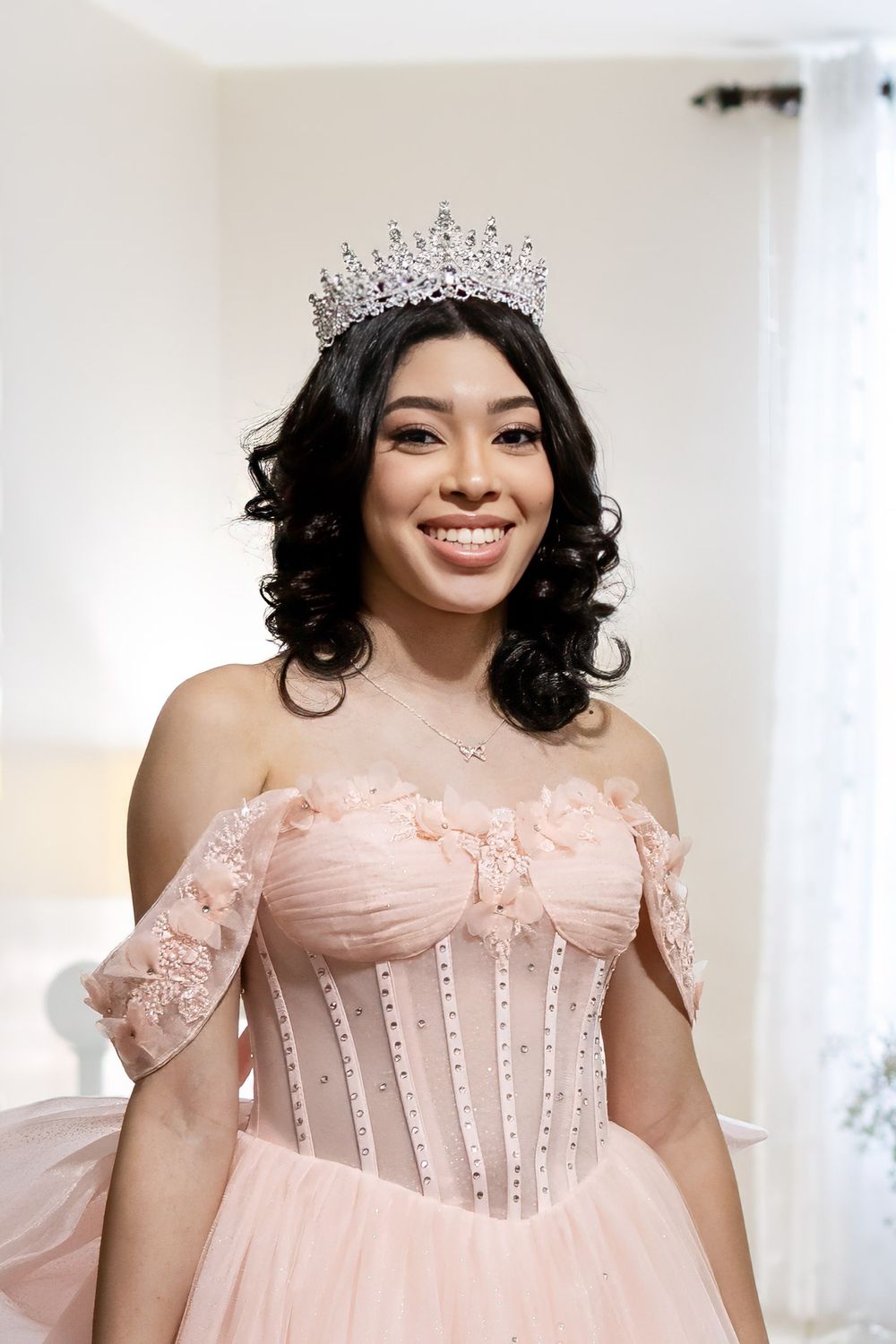 Close-up portrait in a pink princess gown with tiara and curled hairstyle.