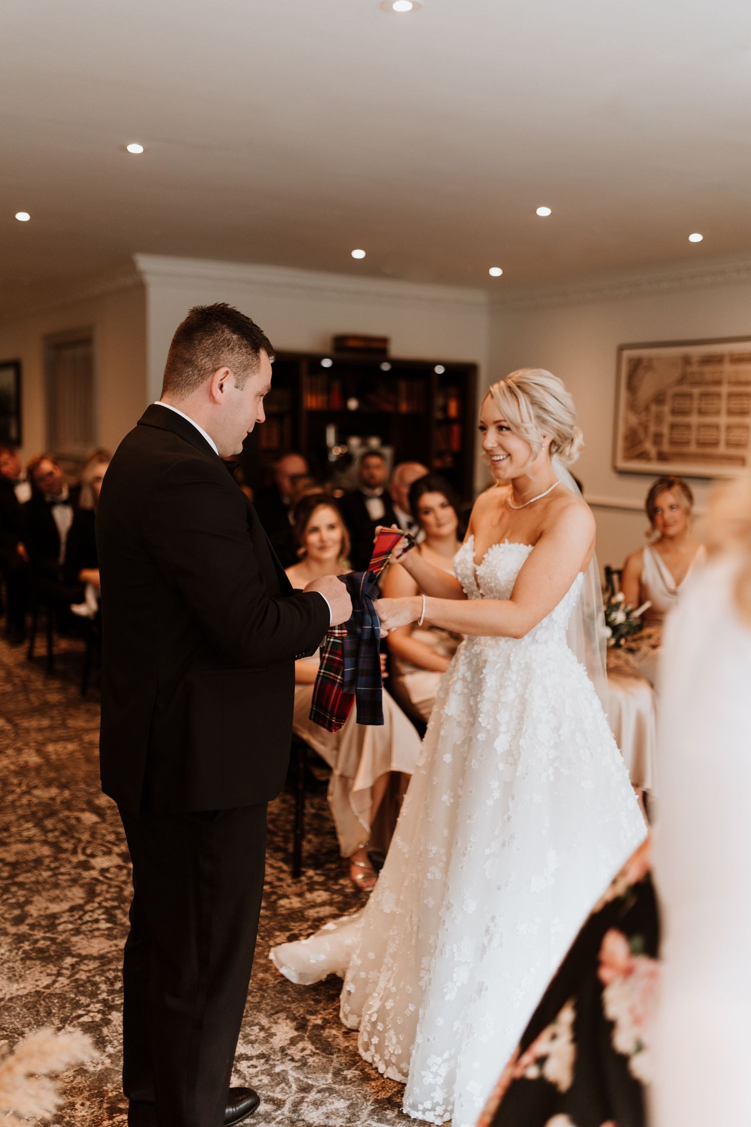 A joyful candid moment during a wedding ceremony as two people exchange vows in an elegant indoor setting.