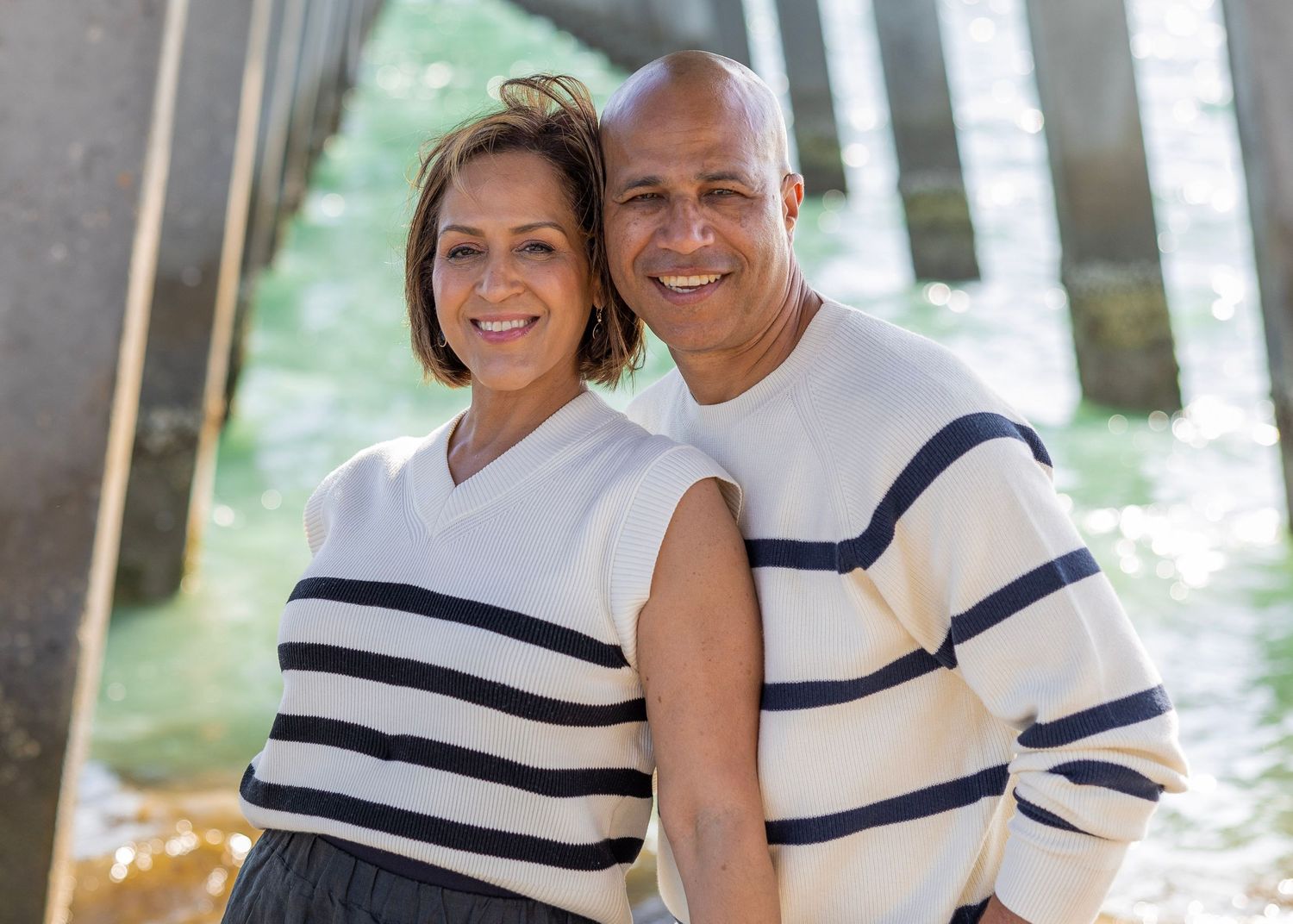 Couple in matching white and navy striped outfits pose together outdoors.