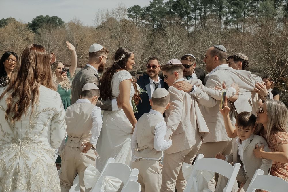 A group of wedding guests dressed in light colors gathered outdoors.