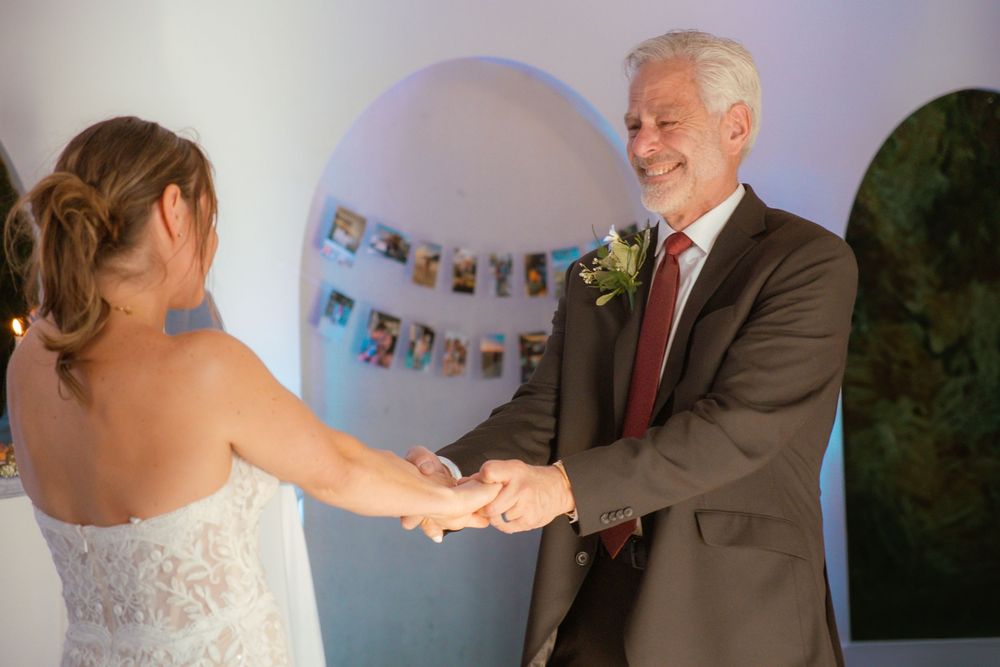 A special dance moment between two people at a wedding reception with photo display in background.
