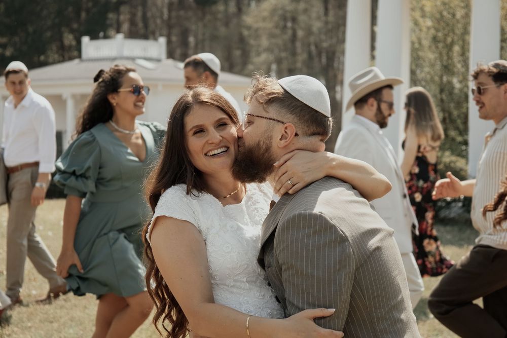A joyful wedding celebration with guests in the background and a happy couple in the foreground.