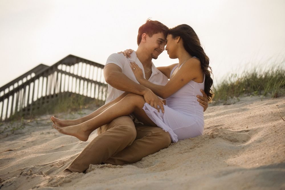 Couple relaxing and sharing intimate moments on sandy beach steps.