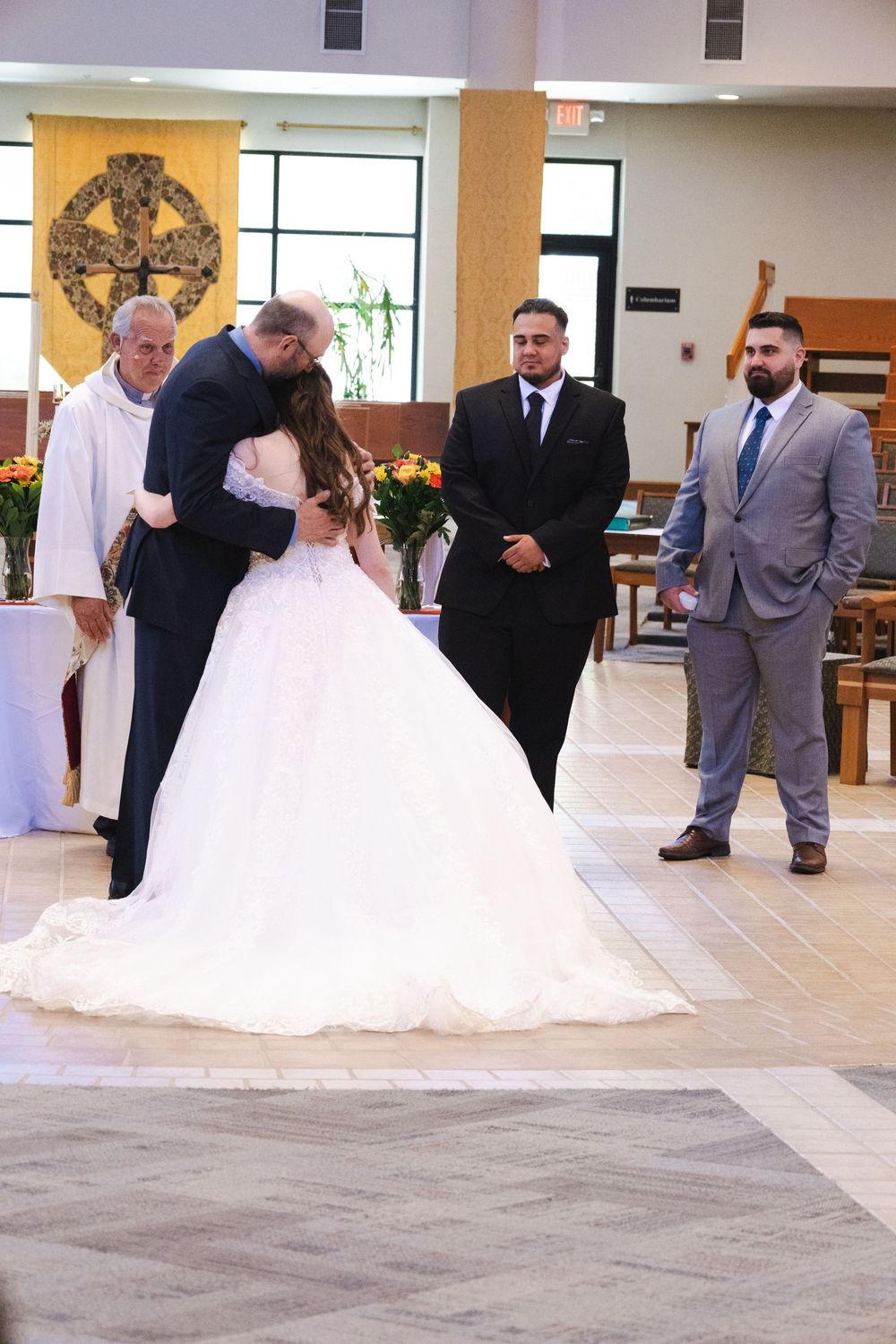 A wedding ceremony moment captured in a church with floral decorations and formal attire.
