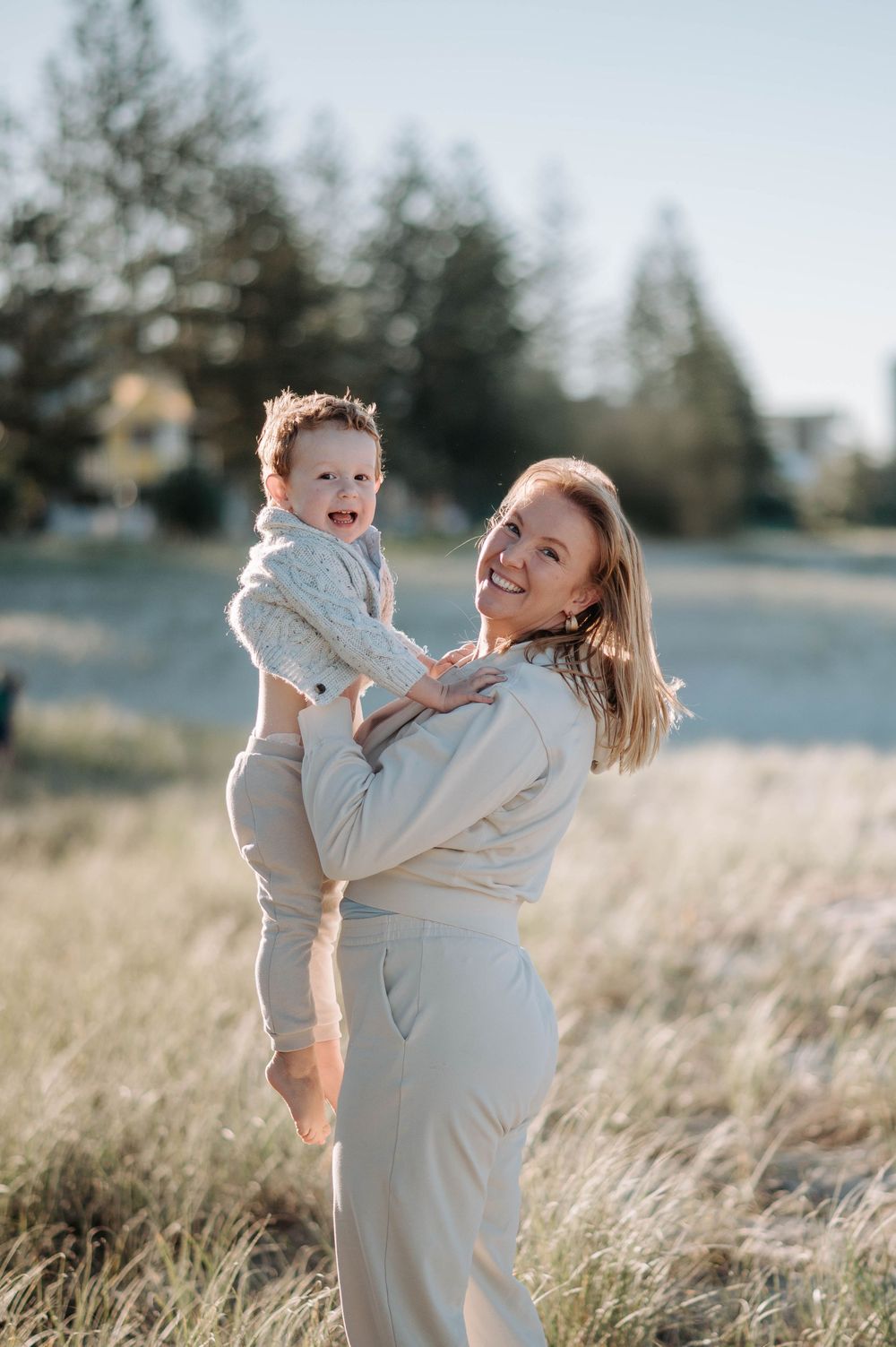 A heartwarming moment captured in a sunlit field as two people share laughter and embraces.