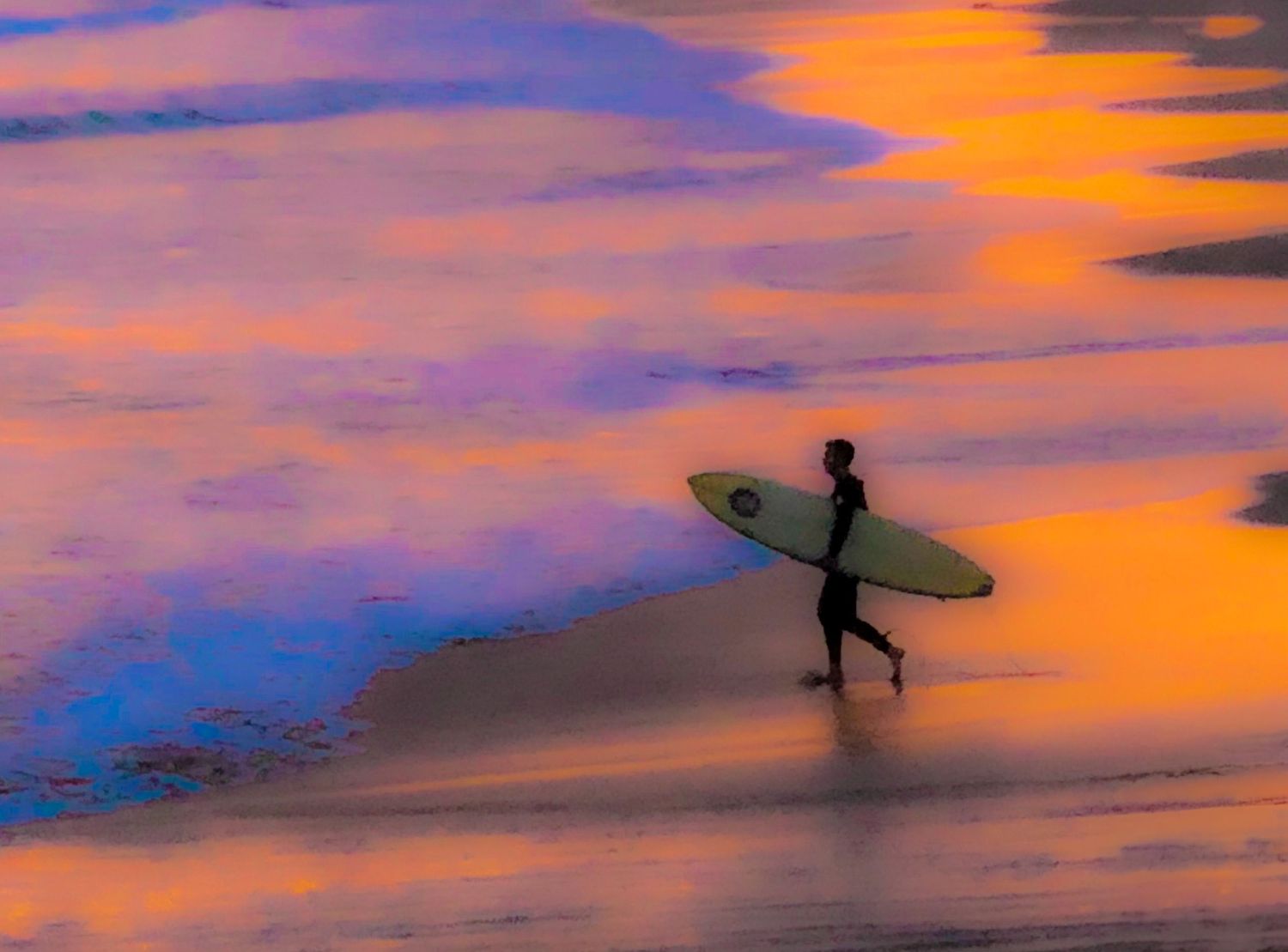 Silhouette of a surfer walking along beach at sunset with vibrant purple and orange sky.