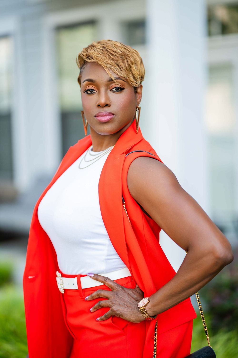 Professional portrait in orange blazer and white top against column background.