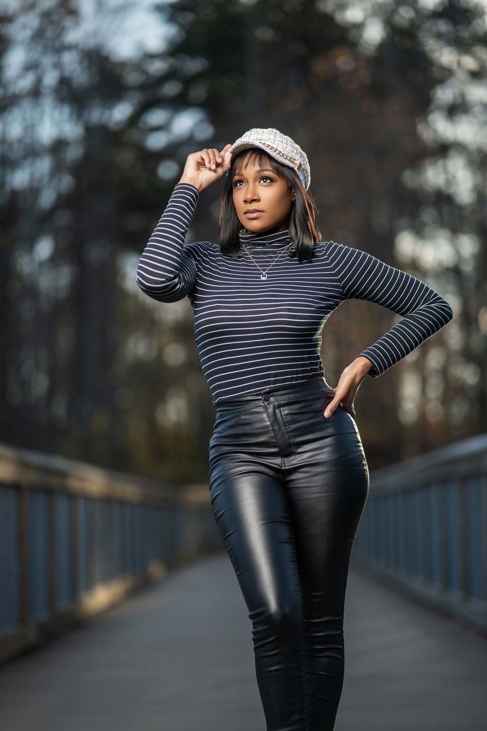 Fashion portrait on bridge wearing striped turtleneck, leather pants and knit cap.
