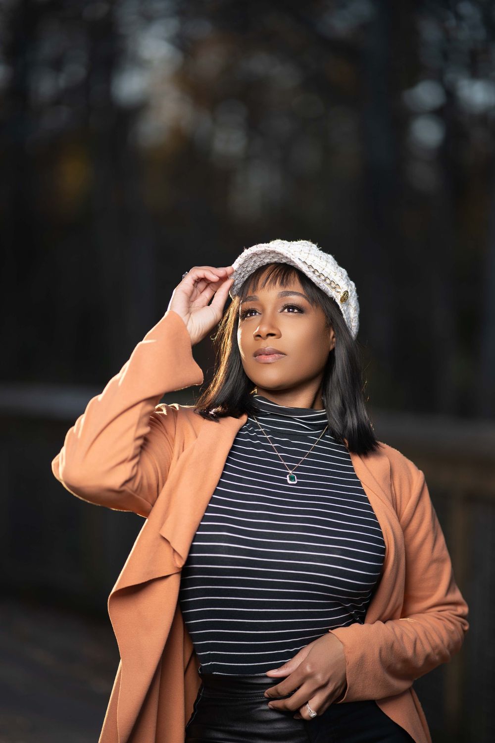 Fashion portrait in peach blazer and striped top with knit cap outdoors.