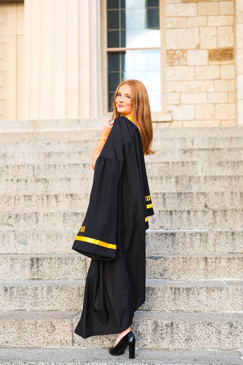 Graduation portrait series showing graduate ascending stone steps in black academic regalia.