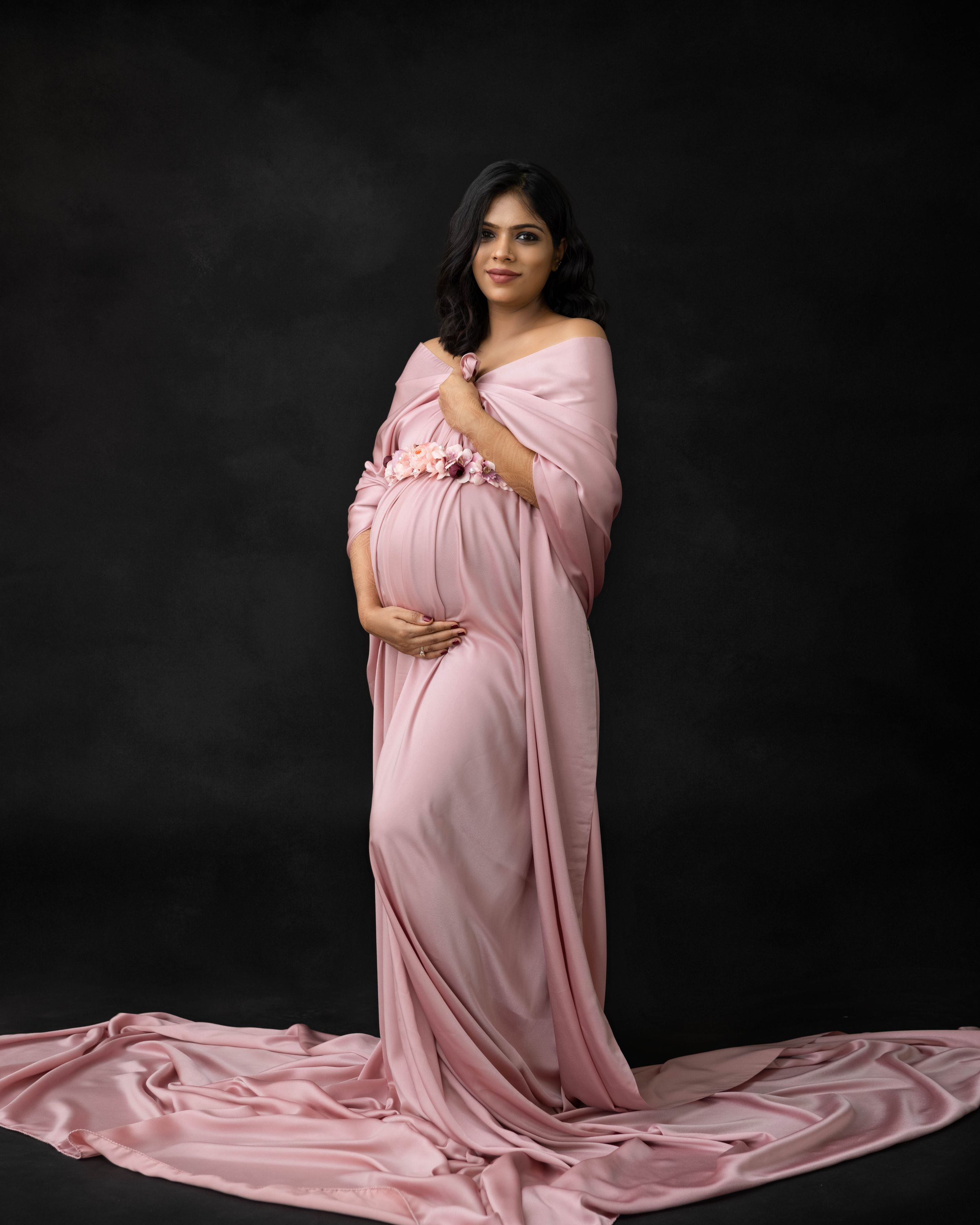 Graceful maternity portrait in off-shoulder pink silk gown with long train.