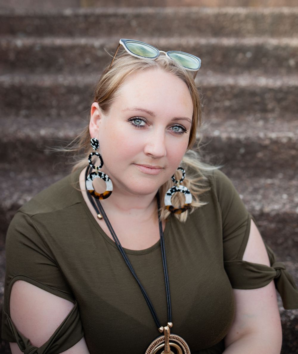 Casual portrait of woman from the chest up sitting on concrete stairs outdoors at Bastion Point, Auckland