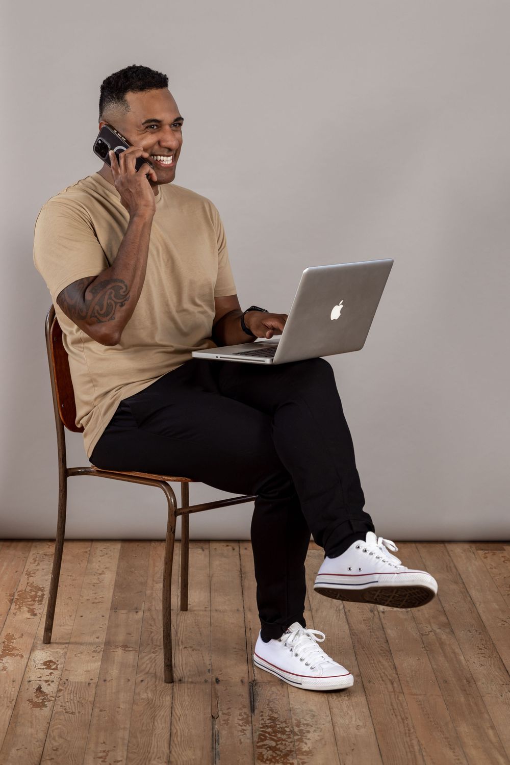 Pacific Island male sitting down on laptop and phone. Professional portrait branding photoshoot