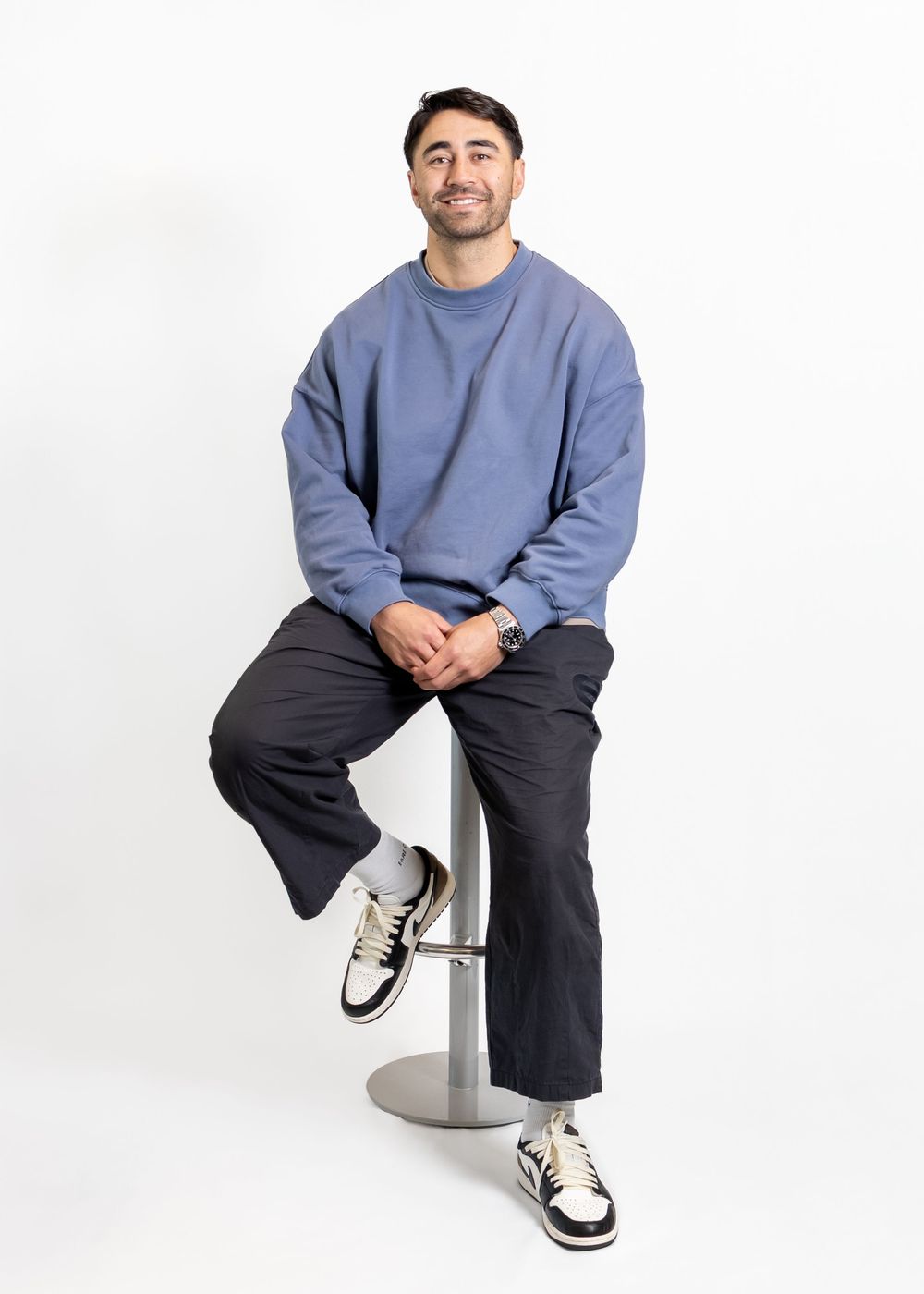 Shaun Johnson full body portrait. New Zealand Warriors league player. Sitting on chair casually white white studio background for photoshoot