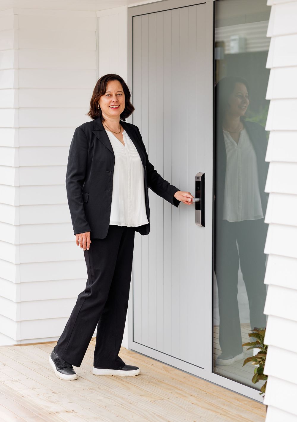 Female Real Estate agent in front of house clutching the door handle to open the door.