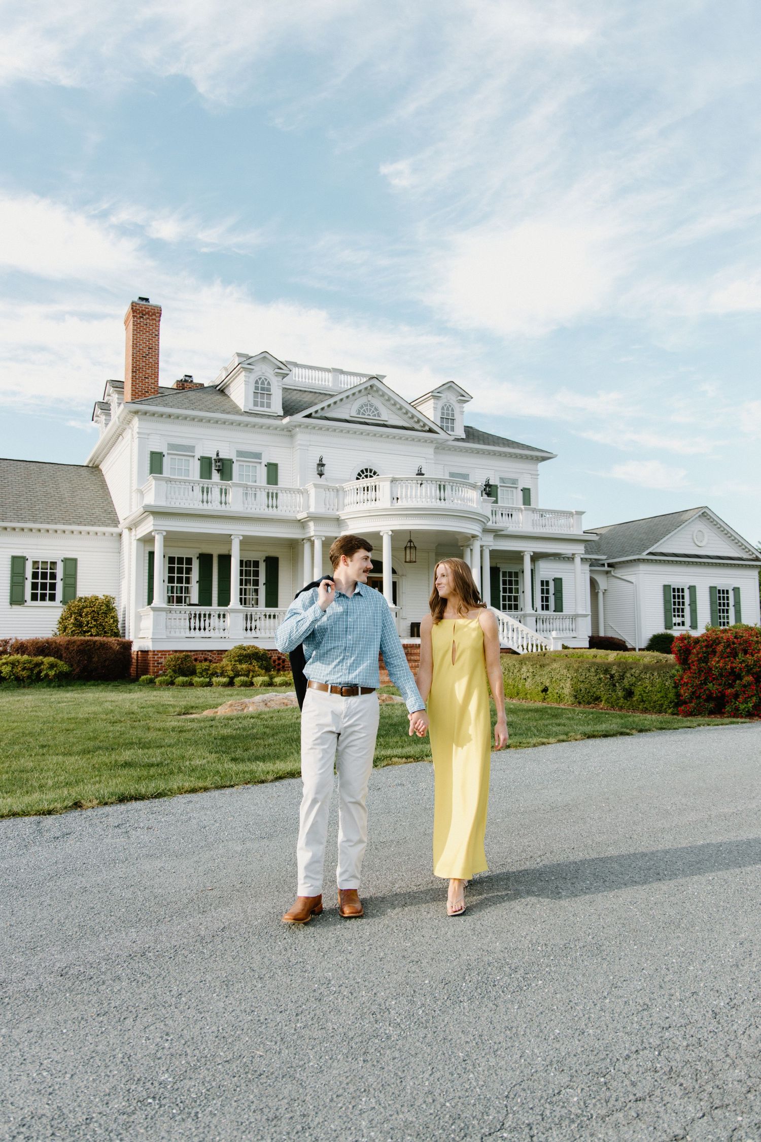Beautiful white colonial estate with dormers and brick chimney seen from multiple angles against a bright blue sky with clouds.