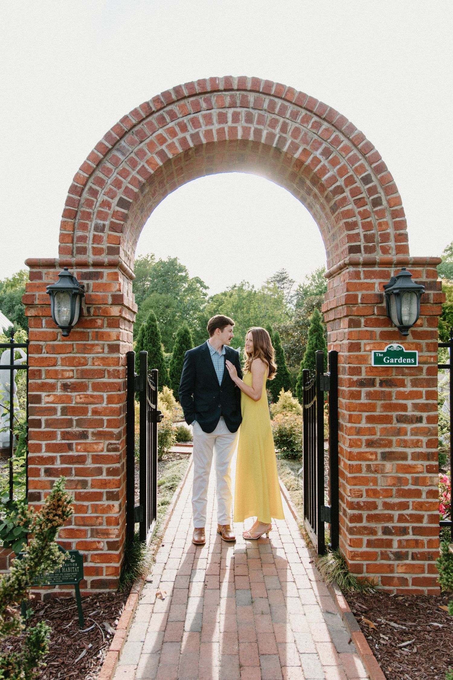 A sequence of five wedding photos showing figures walking through a brick garden archway at sunset.