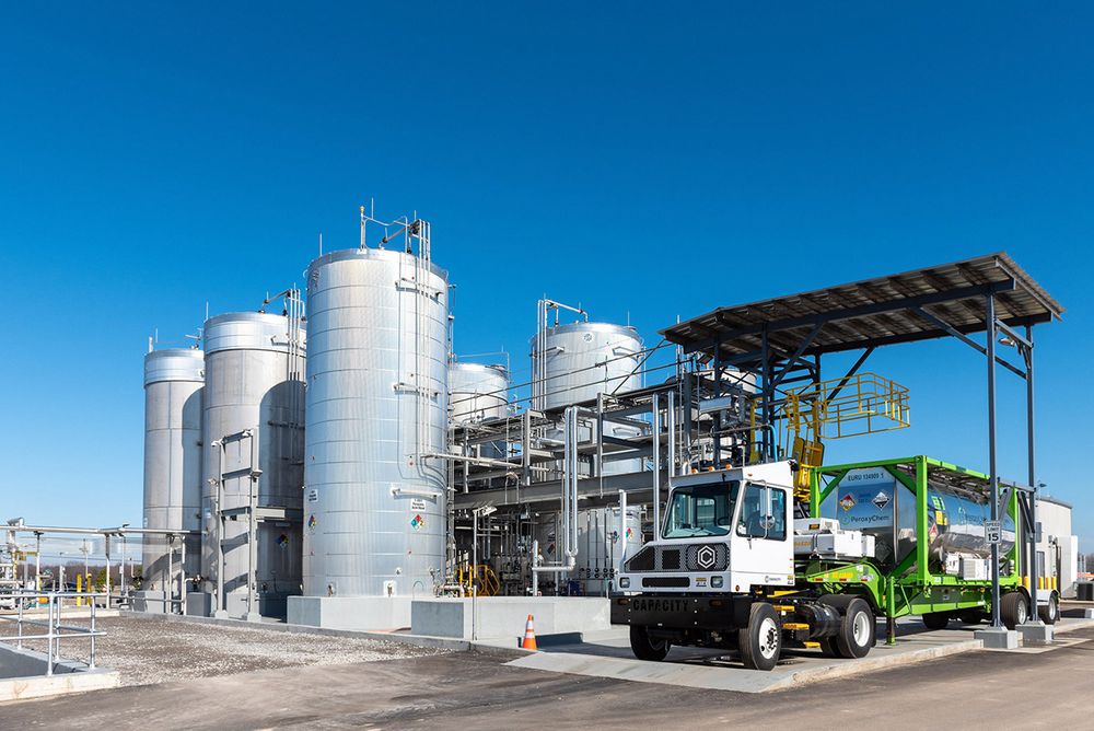 Industrial chemical storage tanks and equipment at a PeroxyChem facility against blue sky.