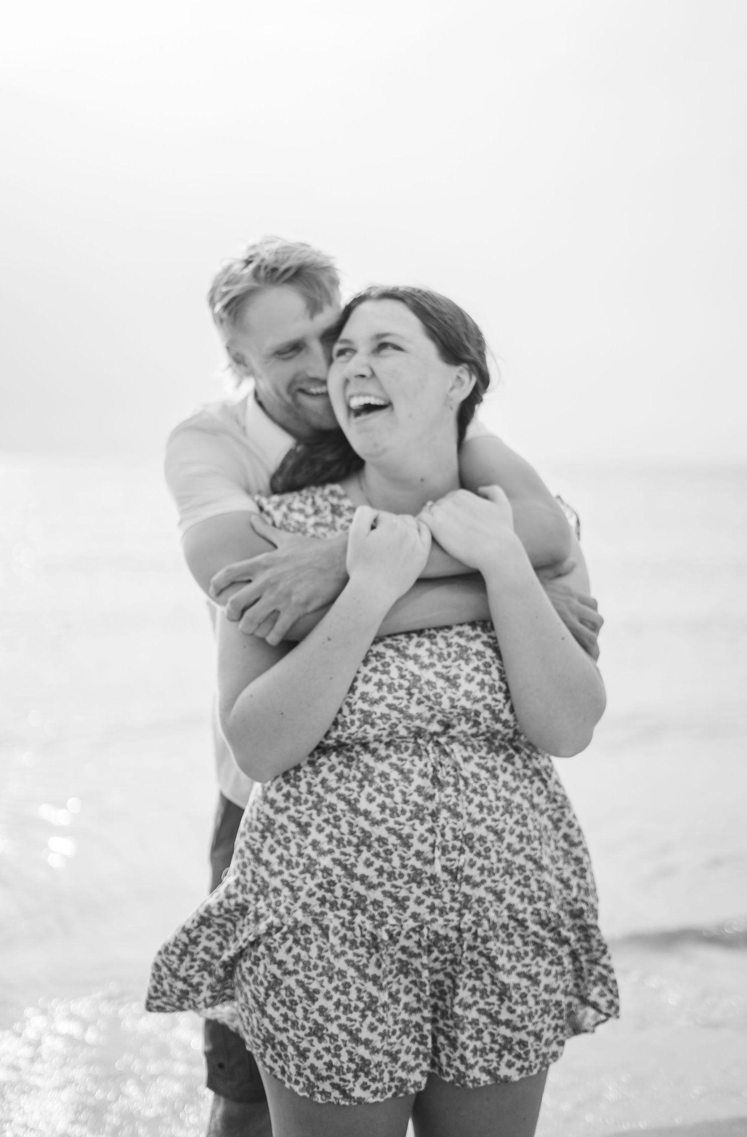 A black and White picture of a couple hugging on the beach.