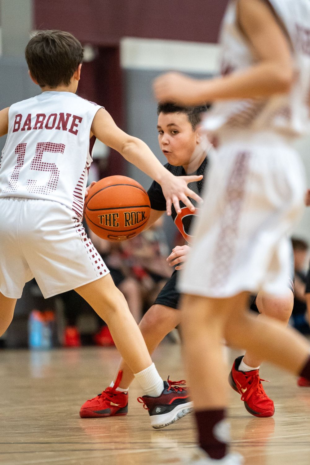 Basketball players compete during a game with one wearing red shoes and jersey number 15.