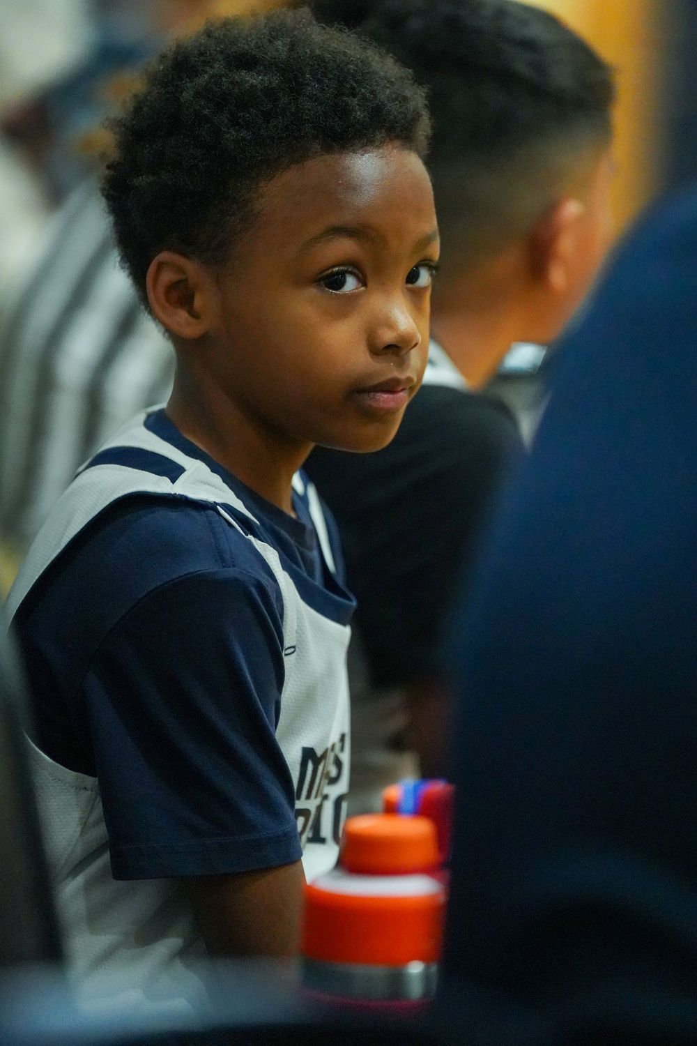 A student in a navy uniform smiles while sitting at a table during a school activity or mealtime.