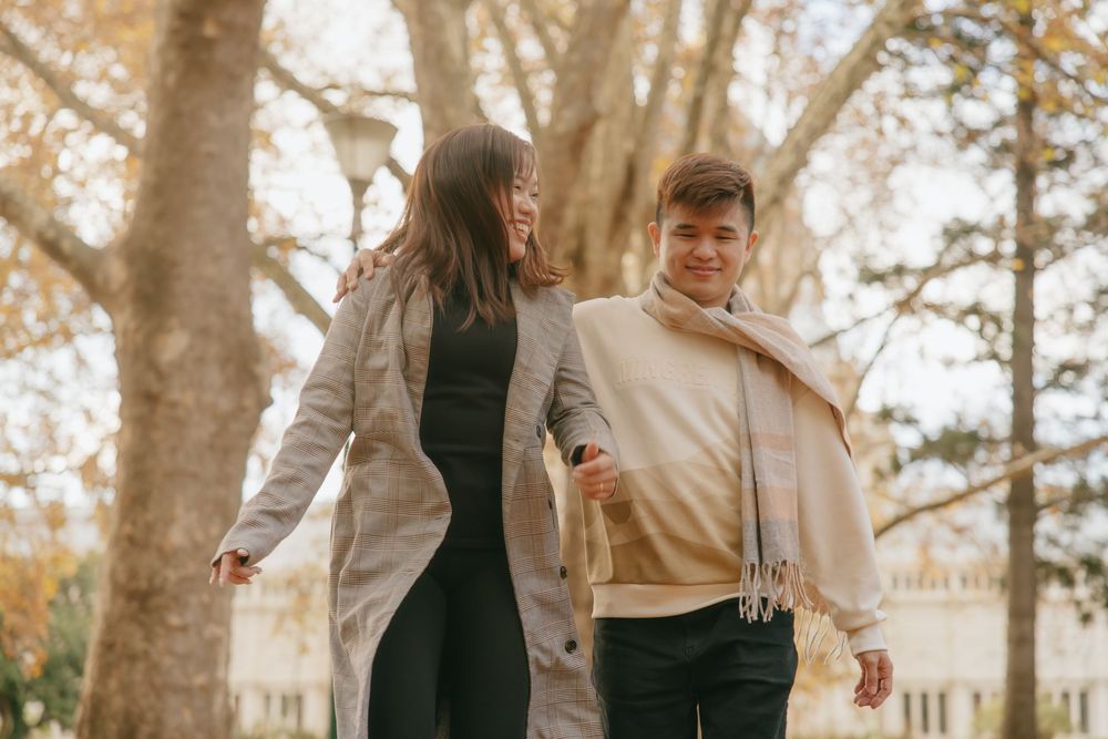 Couple sharing intimate moments during fall photoshoot between majestic trees.