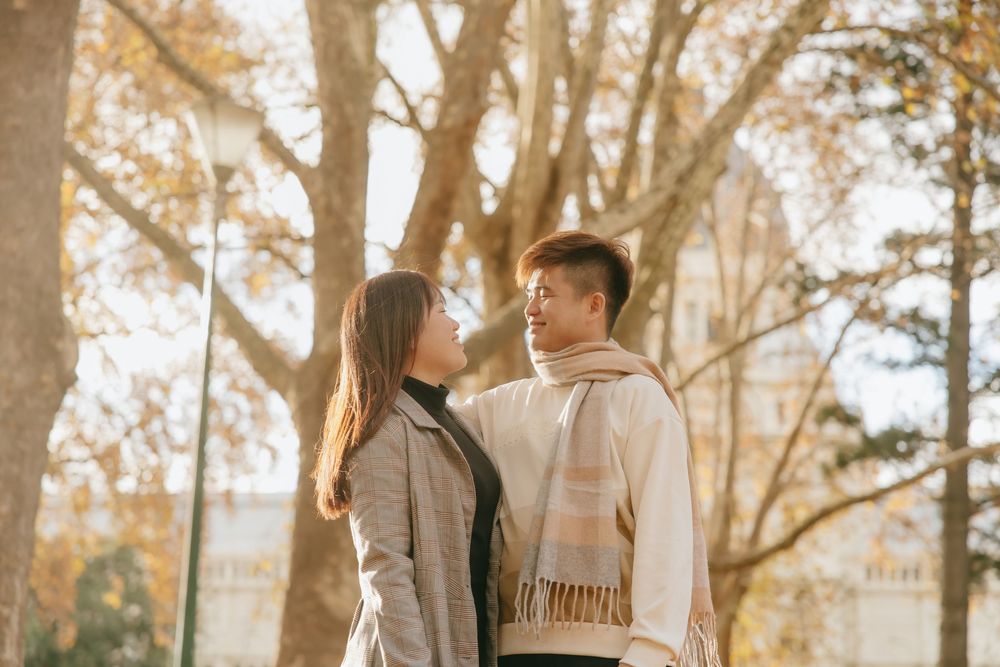 Romantic couple in warm clothing sharing a tender moment among fall foliage.