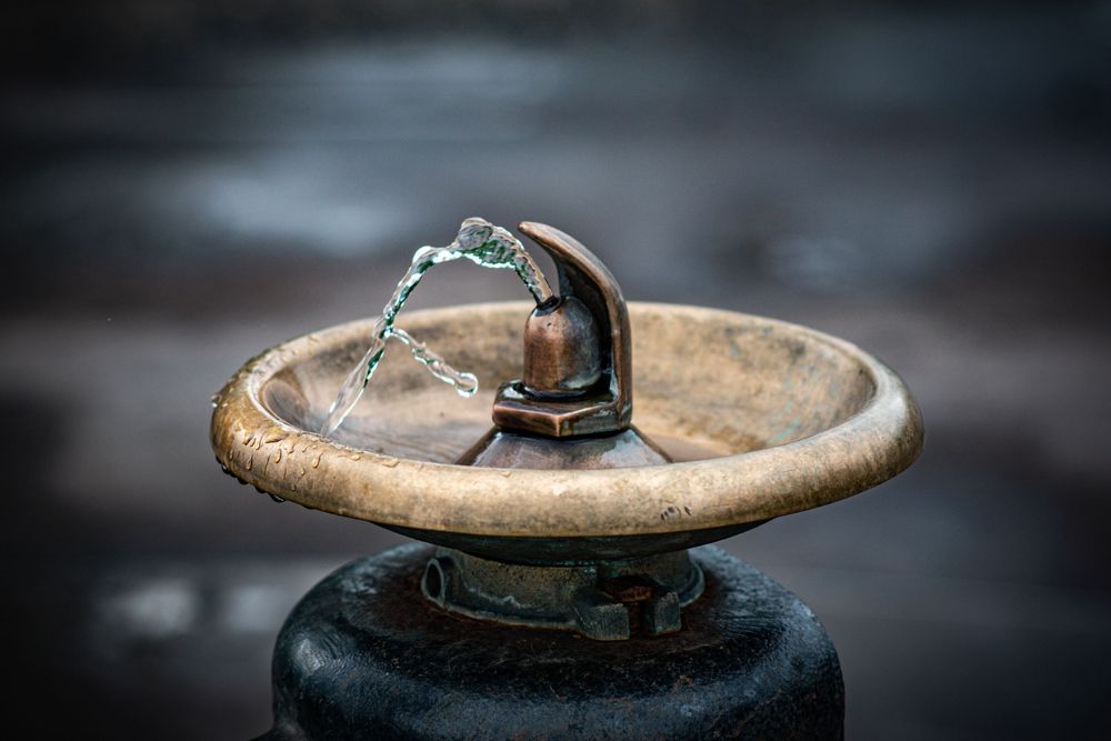 Close-up of a rustic metal tap head with blurred background.