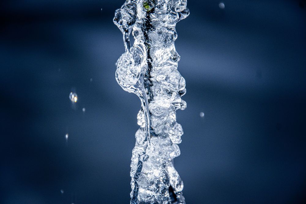 Frozen water droplets forming intricate ice patterns against a dark blue background.